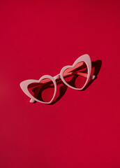 Heart shaped sunglasses on the red background. Valentine's day concept composition