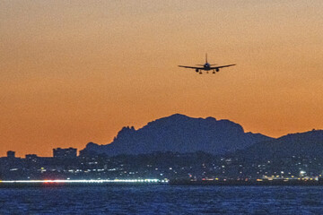 Fototapeta na wymiar Avion en phase d'atterrissage à l'aéroport de Nice Côte d'Azur dans le coucher de soleil