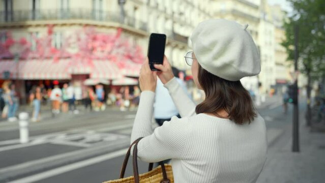 Attractive girl taking photo of French street bistro