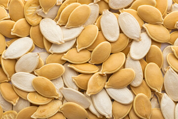 Yellow and white unpeeled pumpkin seeds. Background, texture. top view