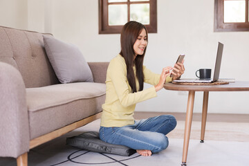 Fototapeta premium Leisure activity concept, Young woman surfing social media on phone while sitting to relax on floor