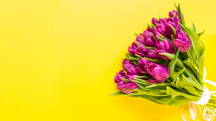 Beautiful romantic bouquet of pink tulips on the yellow background. Lots of tulips, large bouquet. Valentines day, Womens day or Mothers day celebration concept. Copy space