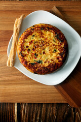 Potato omelette with vegetables on a wooden board