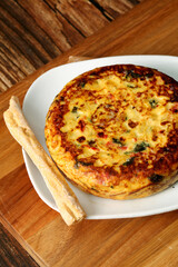 Potato omelet with vegetables on a wooden board