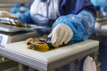 Fish factory worker weighs pieces of smoked mackerel.