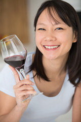 asian woman holding a glass of red wine