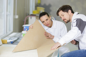 man explaining woman woodworking tips in wood workshop