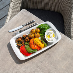 Plate with grilled vegetables on grey stone table.