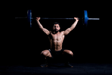 Muscular man doing snatch exercise with barbell