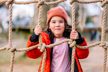 Smiling girl climbing on rope net