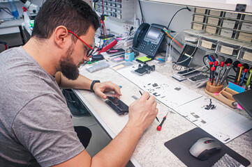 Electronics repair shop, a repairman is surrounded by tools and equipment. A technician repairs,...