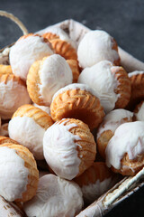 Cupcakes in large quantities are in the basket. White icing on cupcakes. Baking for the Easter holiday. Vertical photo.