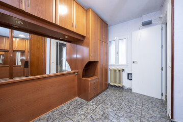 Bedroom without bed with bridge furniture on the mezzanine and built-in wardrobe with sliding mirror and wooden doors, cast iron radiators and ugly stoneware floors