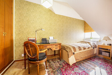 Bedroom with single bed, built-in wardrobe and vintage wooden desk in a room with sloping ceilings