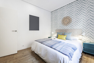 Bedroom with double bed with upholstered headboard, blue metal bedside tables and chestnut wooden flooring