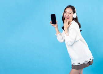 Naklejka premium Happy young woman in headphones listening to music on light blue background. Smiling caucasian young woman listening to the podcast e-book music song singer rock band in headphones earphones.