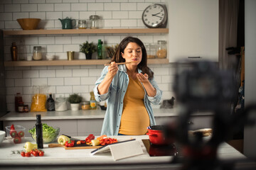 Beautiful pregnant woman filming cooking vlog. Happy woman filming her blog about healthy food at home.