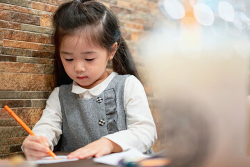 Back to school. Happy smiling pupil drawing at the desk. Cute little preschooler child drawing at home. Kid girl drawing with pencils
