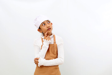 Thoughtful little girl in chef uniform thinking something and looking at empty space. Isolated on white background