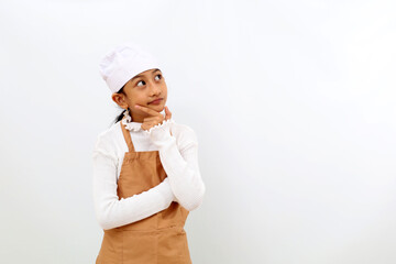 Thoughtful little girl in chef uniform thinking something and looking at empty space. Isolated on white background