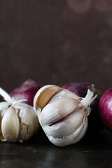 Garlic bulb and onions on a dark table, raw garlic and onions , Allium sativum and Allium cepa
