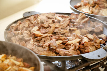 Pratos na mesa com carne na panela e salada lindas de ver.