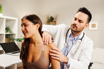 Young woman with shoulder pain is being examined by a physiatrist