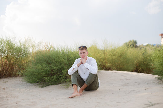 a man in a white shirt sits on the sand dunes