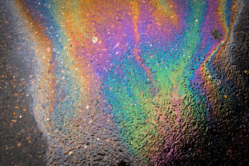 Oil stains from leaks in the car engine. Oil after rain makes spots with rainbow reflections...