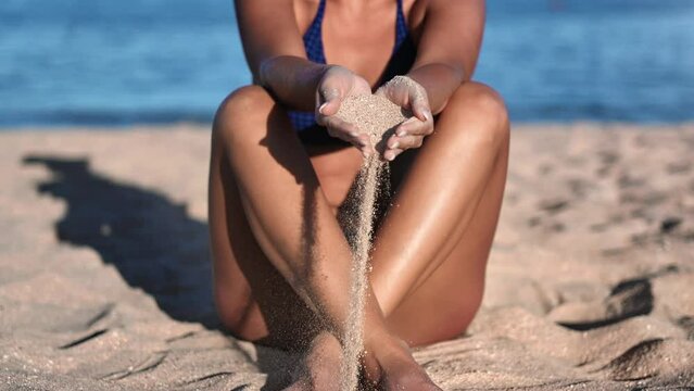 Unrecognizable woman beauty body bikini pouring sand through hand finger sea beach summer vacation