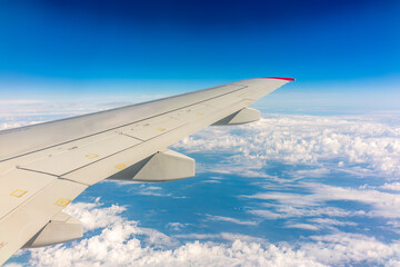 Fototapeta premium View from the airplane window at a beautiful cloudy sky and the airplane wing