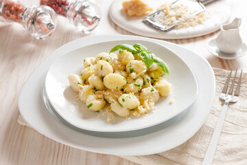 Traditional homemade cooked italian potato gnocchi with butter, parsley and parmesan cheese on white wooden background