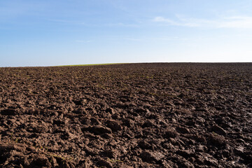 Plowed agricultural hill on a sunny day with blue sky in spring