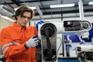 Male engineer worker using screwdriver maintenance automatic welding robotic arm machine. Male technician worker checking, repair automatic welding robot arm machine