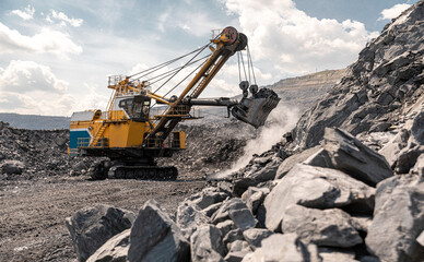 Large quarry dump truck. Big yellow mining truck at work site. Loading coal into body truck. Production useful minerals. Mining truck mining machinery to transport coal from open-pit production