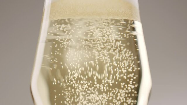 Glass of champagne on white isolated background. Champagne bubbles. Slow motion and super macro shot of tiny air bubbles flowing upwards in elegant glass of champagne on a white background