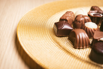 Golden tray with various chocolates. Concept of sweets, celebration, Valentine's sweets. copy space