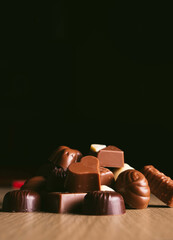 Mountain made with chocolates of various shapes and sizes on a black background. Concept of sweets, celebration, Valentine's sweets. vertical photography and copy space