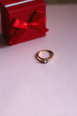 Engagement ring in elegant red box. Pink background, selective focus.