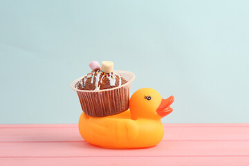 Rubber duck with Appetizing cupcake on a pastel background