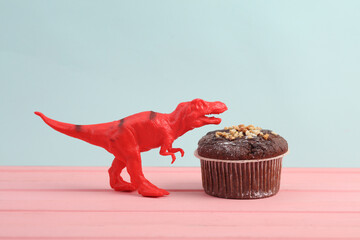 Toy tyrannosaurus rex with Appetizing cupcake on a pastel background