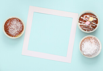Cupcakes with a white empty frame on a blue background. Top view