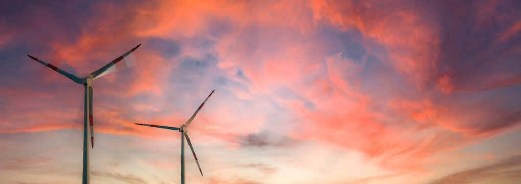 A rotating and a stopped wind turbine at a beautiful sunset sky