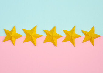 Five origami paper stars on pink blue pastel background. Service rating