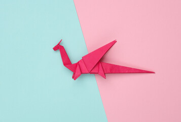 Origami dragon on a blue-pink background. Symbol of the year