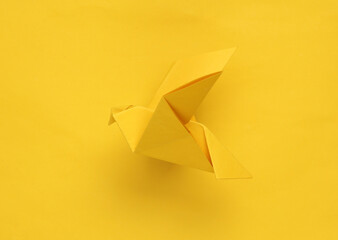 Yellow origami dove on yellow background