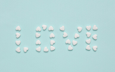 Word love laid out with heart shaped pills on a blue background. Medicine, love concept