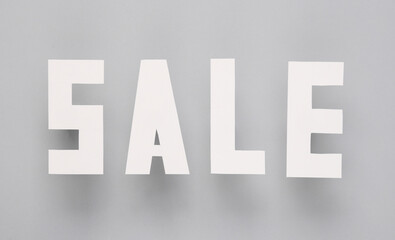 Sale words cut out of paper on a gray background