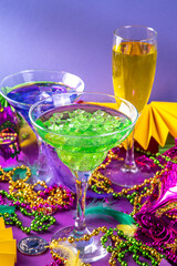 Mardi gras cocktails set. Colorful purple, yellow, green martini champagne wine cocktail glasses for Mardi gras party bar with carnival decor and orleans masquerade masks