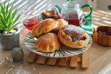 Sweet buns on a plate and hibiscus tea on a wooden table with natural light